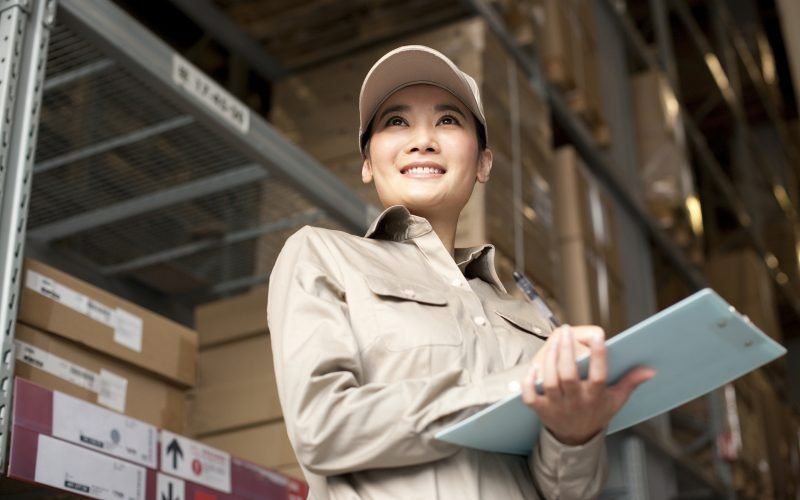 Female Chinese warehouse worker with clipboard